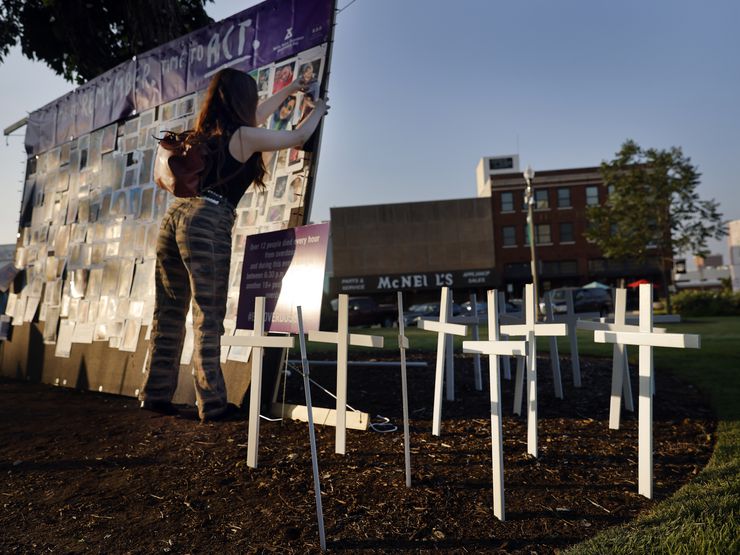 Ashleigh Calvert of Dallas reattached a fallen photo to a memorial wall erected at the North...